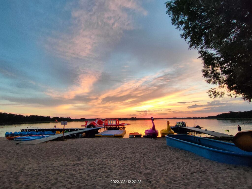 Plaża nad jeziorem- zachód słońca w tle.
