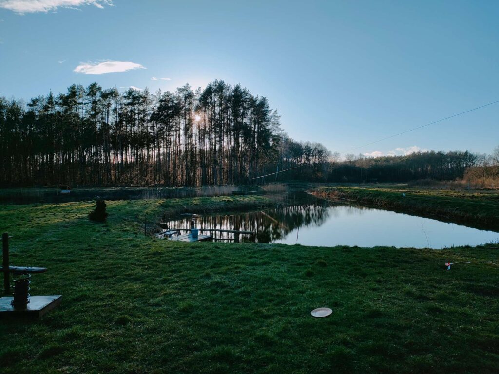 Zachód słońca nad lasem i stawem, agroturystyka, wiejskie życie, wakacje na wsi, slow life.